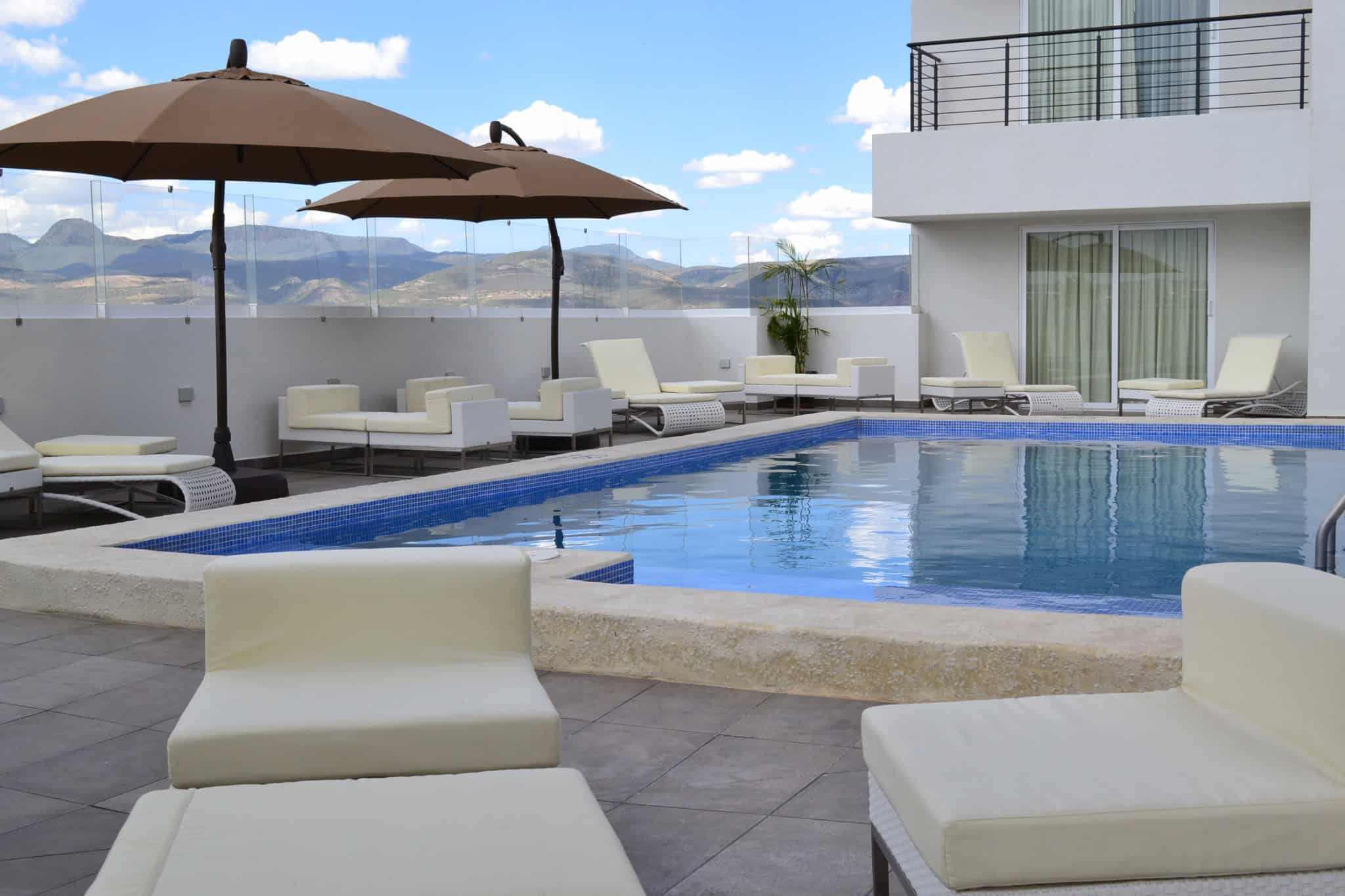 Piscina moderna en hotel de León, México con área de descanso y vista panorámica.