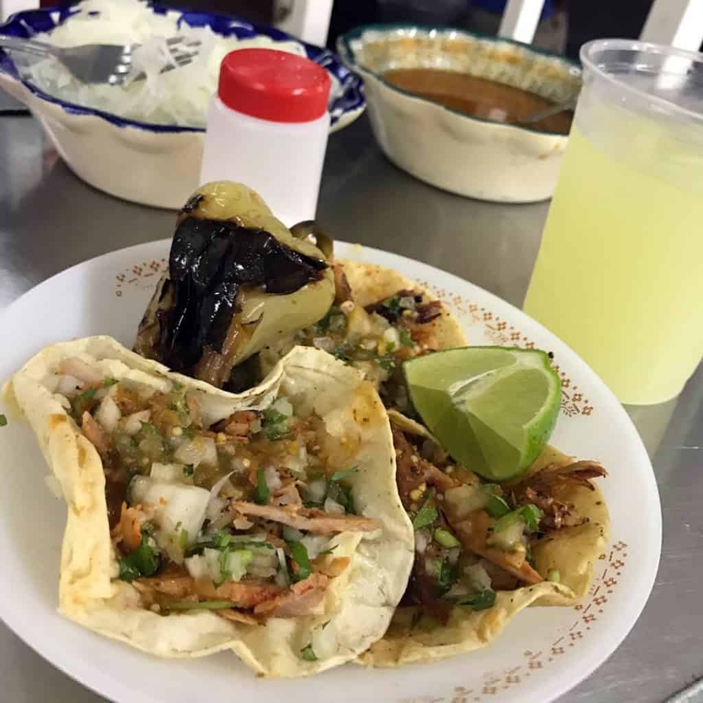 Tacos de pastor con salsa, cebolla, cilantro y lim&oacute;n en un plato tradicional mexicano. Disfruta de sabores aut&eacute;nticos en Le&oacute;n.