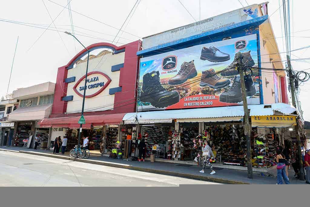 Fachada de la Plaza San Francisco en Le&oacute;n, con tiendas y un cartel publicitario de calzado deportivo.