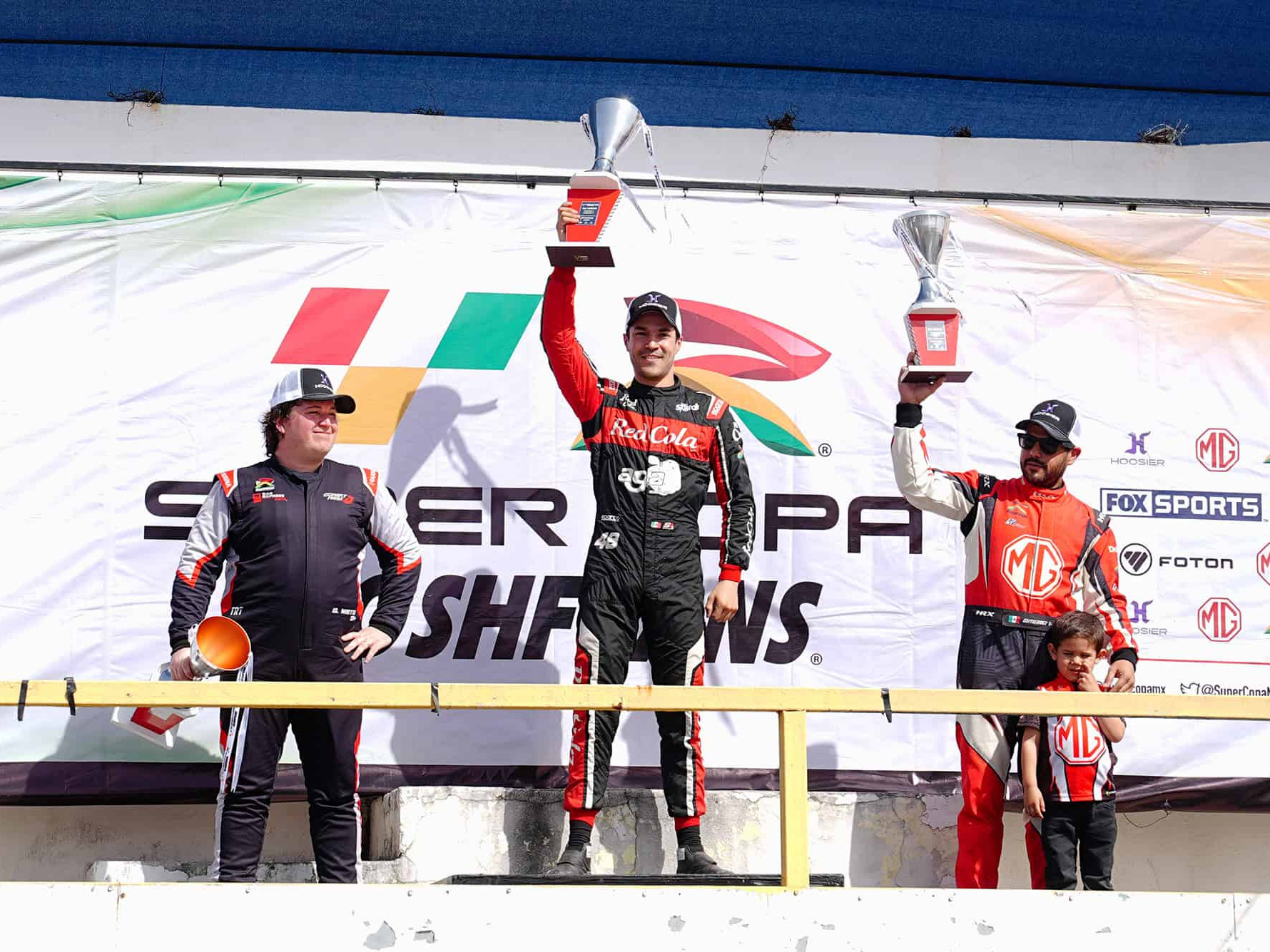 Podio de pilotos en competencia automovilística en León, con tres ganadores en el podio celebrando sus victorias.