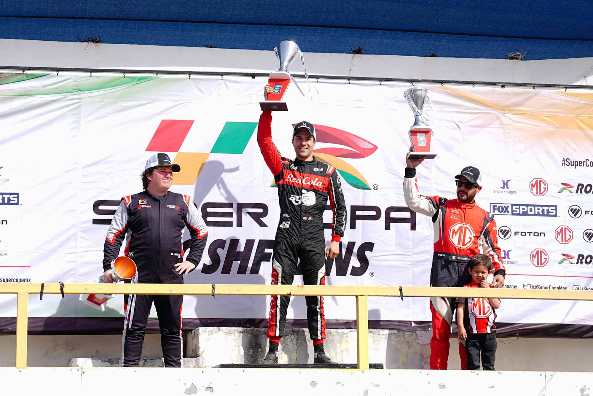 Podio de pilotos en competencia automovilística en León, con tres ganadores en el podio celebrando sus victorias.
