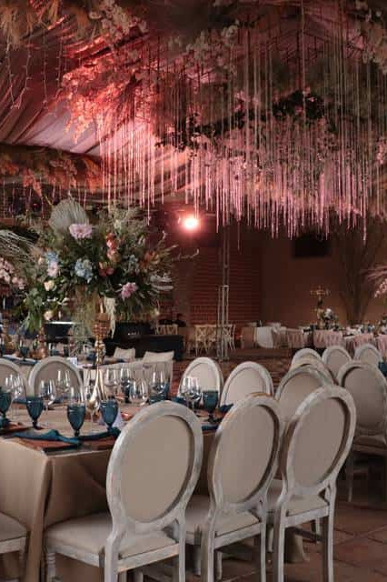 Decoración de boda elegante con flores y luces en salón sofisticado.