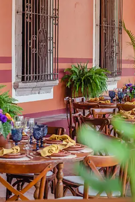 Decoración de mesa para celebración en un hermoso patio con paredes color terracota y vegetación exuberante.
