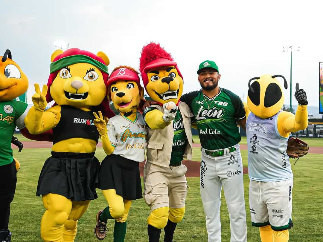 Mascotas de béisbol en León, México, con disfraces coloridos en un estadio deportivo.