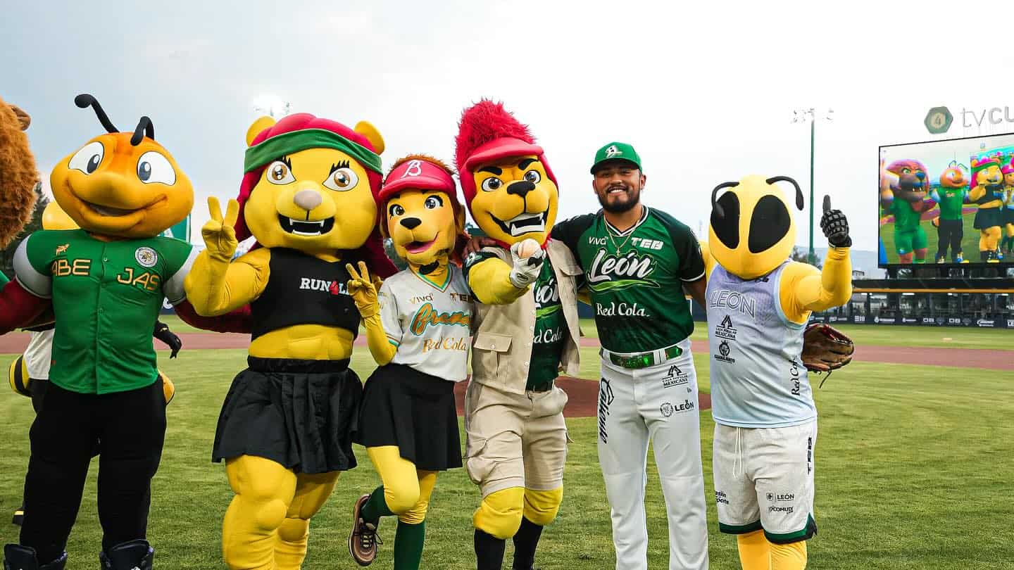 Mascotas de béisbol en León, México, con disfraces coloridos en un estadio deportivo.