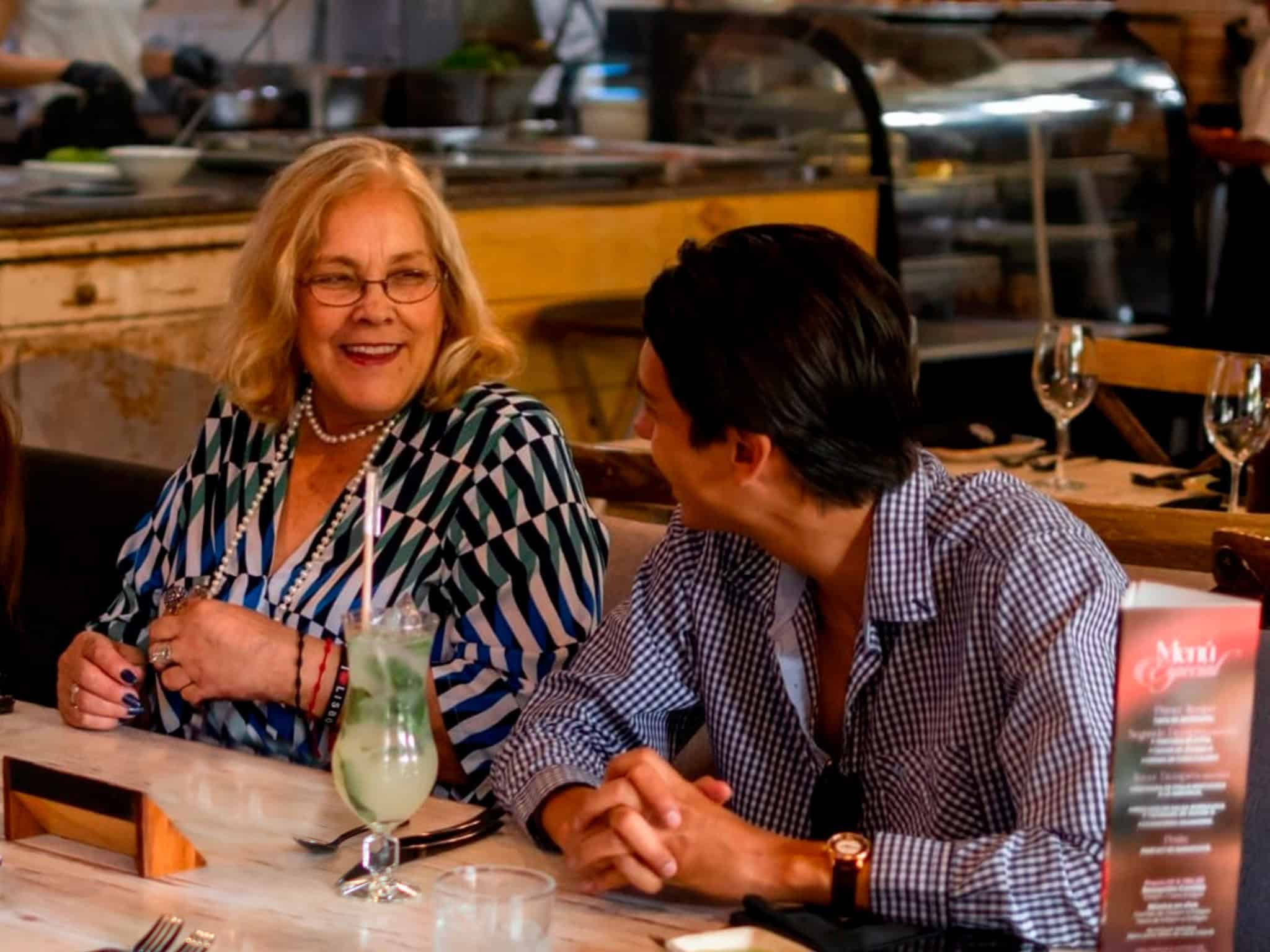 Mujer y hombre conversando y riendo en un restaurante sofisticado en León, con ambiente acogedor y servicio de calidad.