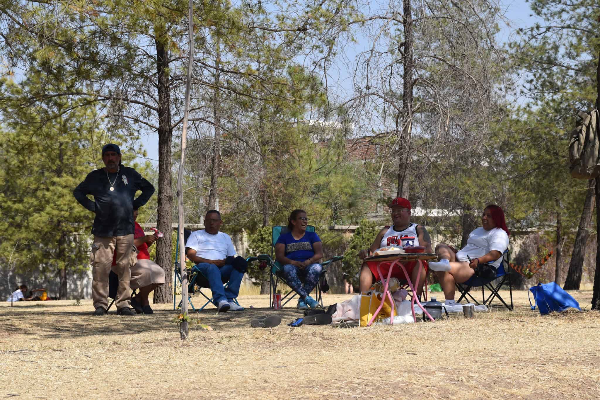 Personas relaj&aacute;ndose en un parque con sillas plegables y naturaleza.
