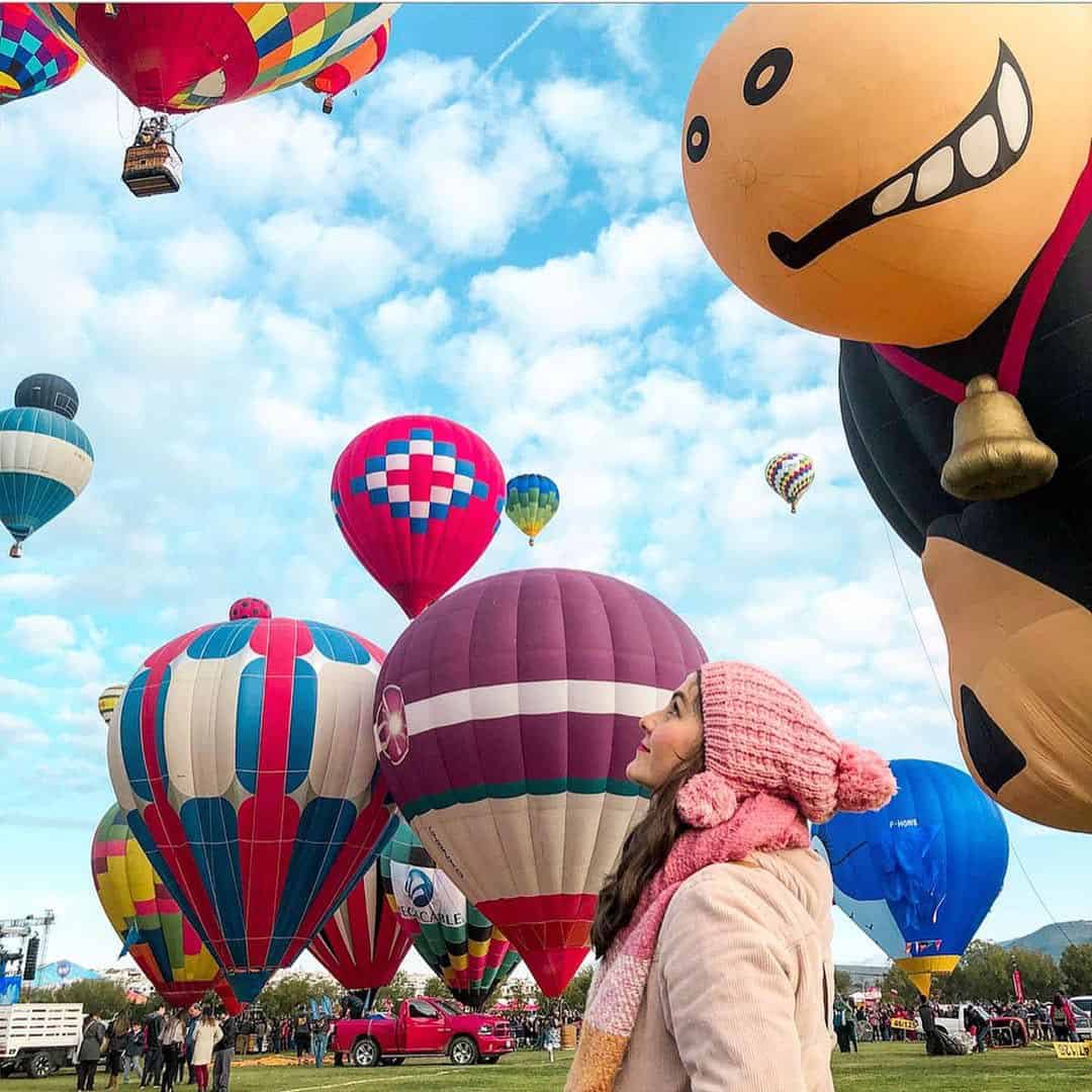 Coloridos globos en el cielo durante festival de globos en Le&oacute;n, con una ni&ntilde;a disfrutando del evento.