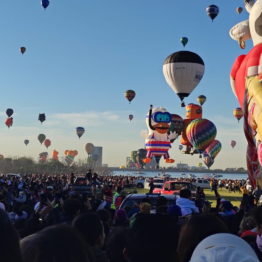 Espectáculo de globos aerostáticos en León, México, con numerosos globos de colores y formas en un evento al aire libre.