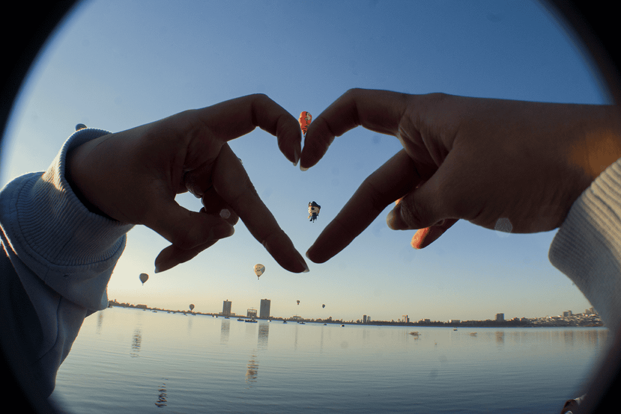 Globos aerost&aacute;ticos en Le&oacute;n, M&eacute;xico, con vista al r&iacute;o y el horizonte urbano al atardecer.