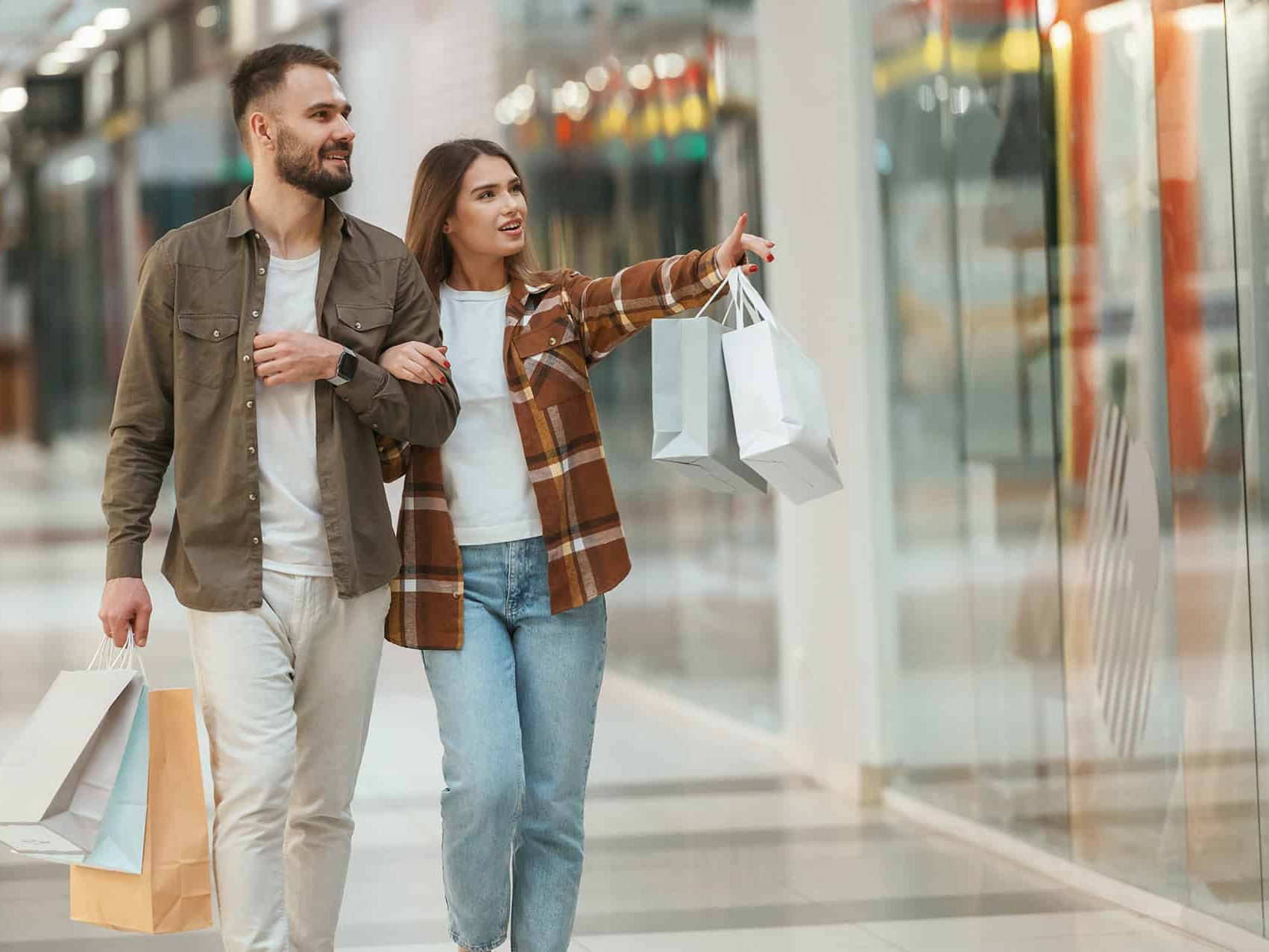 Pareja de turistas disfrutando de compras en un centro comercial en León, México, con tiendas modernas y ambiente animado.