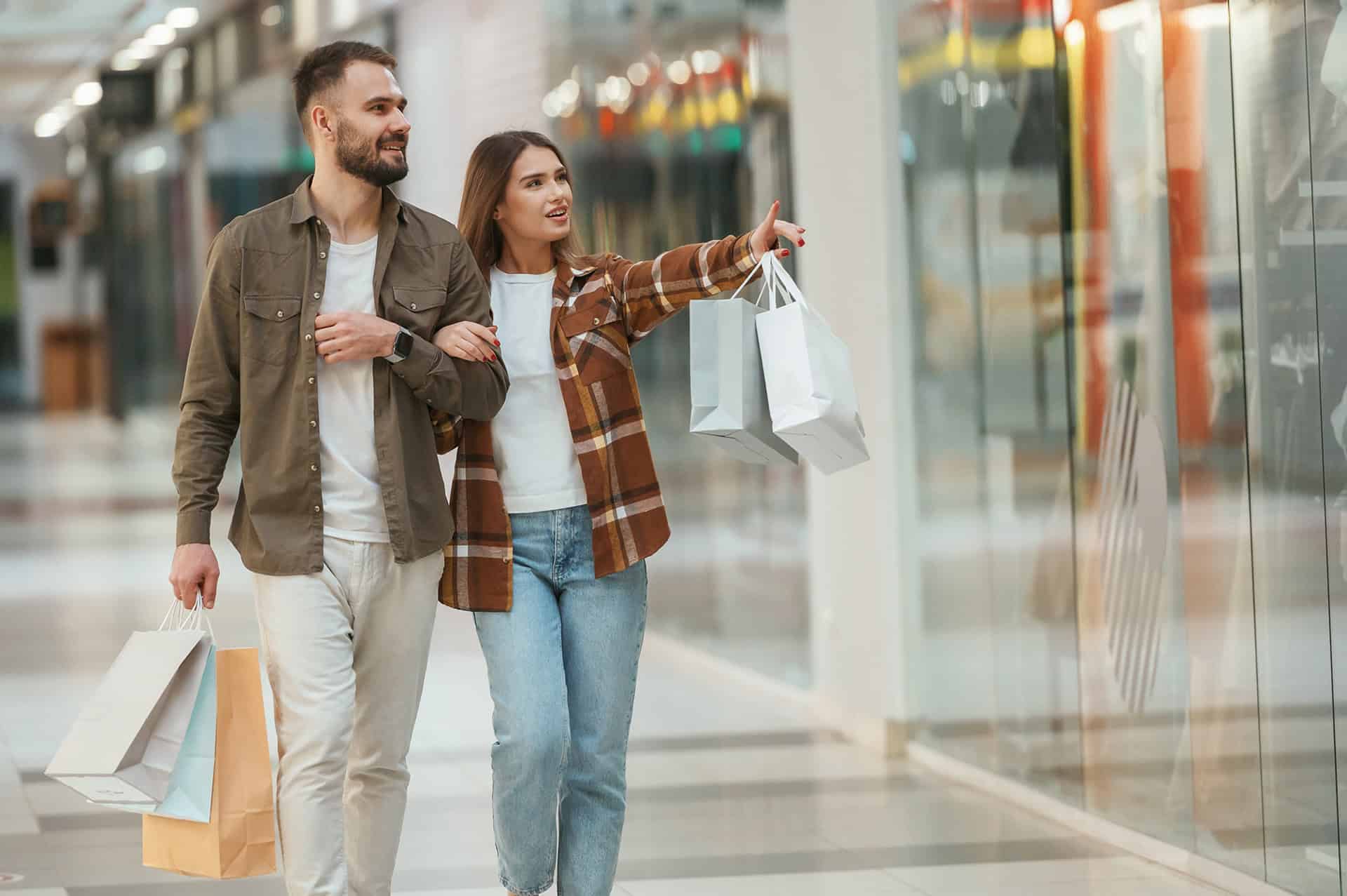Pareja de turistas disfrutando de compras en un centro comercial en León, México, con tiendas modernas y ambiente animado.