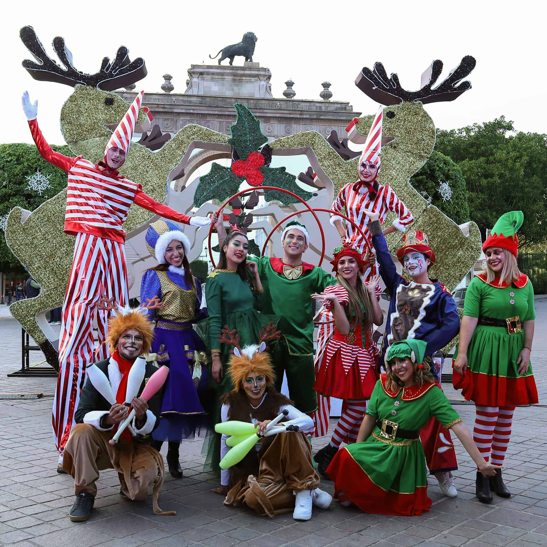 Personas disfrazadas de duendes, renos y personajes navideños en una festividad colorida en León, México.