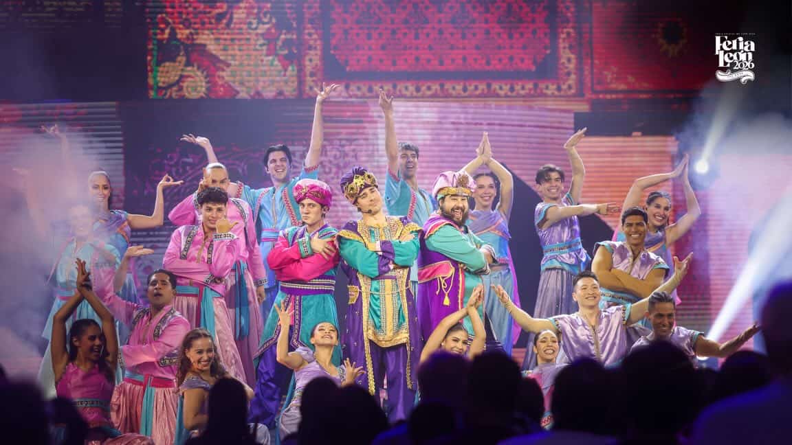 Espectáculo cultural en León, México con bailarines en trajes tradicionales vibrantes y coloridos en un escenario iluminado.