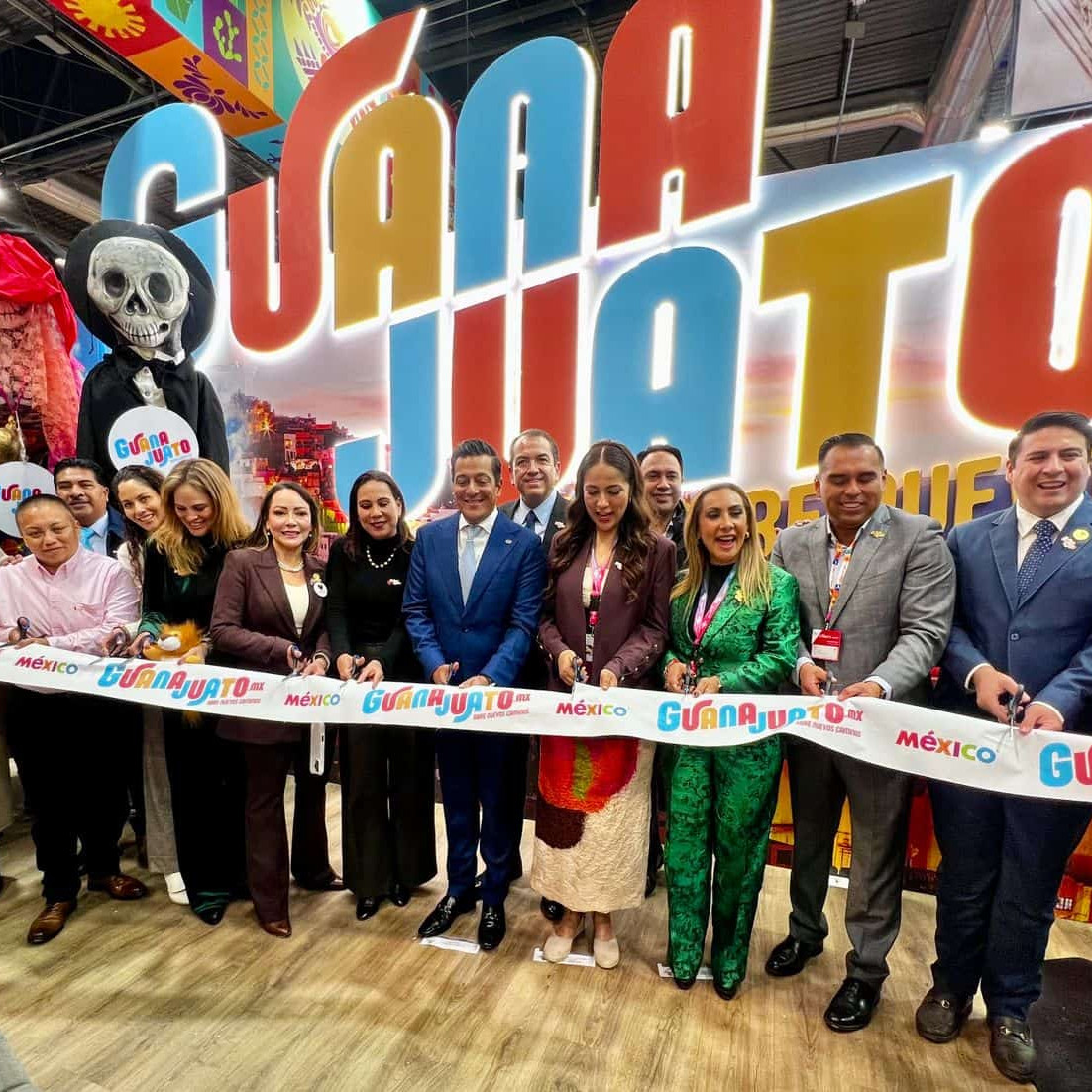 Imagen de grupo en la inauguración de la Feria de Día de Muertos en Guanajuato, con autoridades y visitantes celebrando la tr.