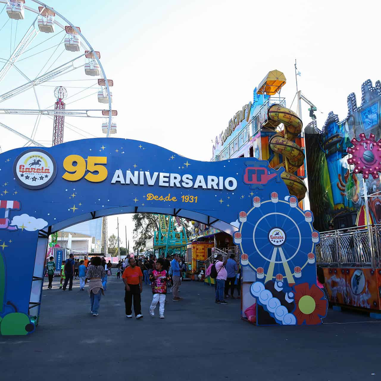 Entrada principal del parque de diversiones con decoración colorida y atracciones en el fondo.