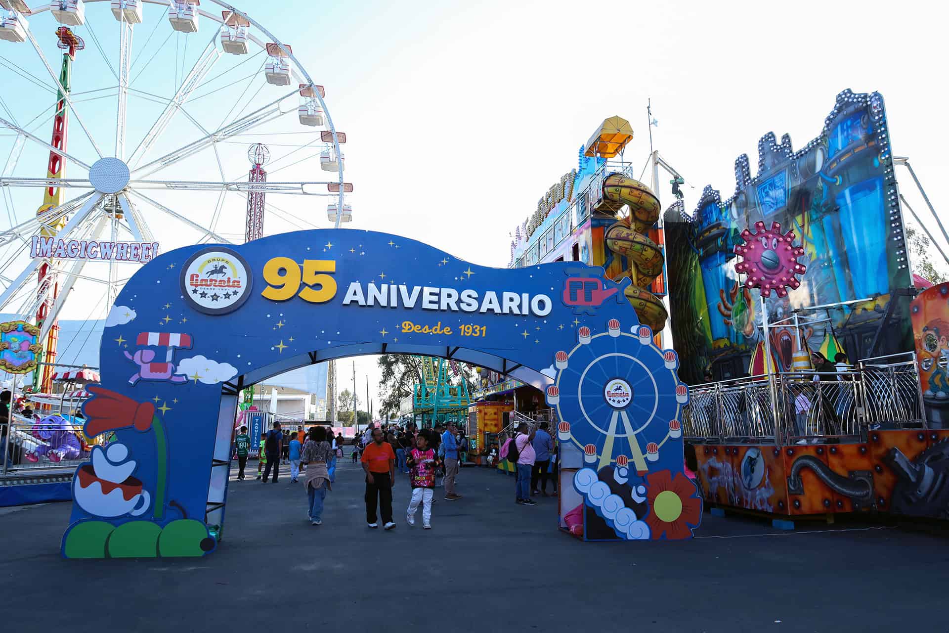 Entrada principal del parque de diversiones con decoración colorida y atracciones en el fondo.