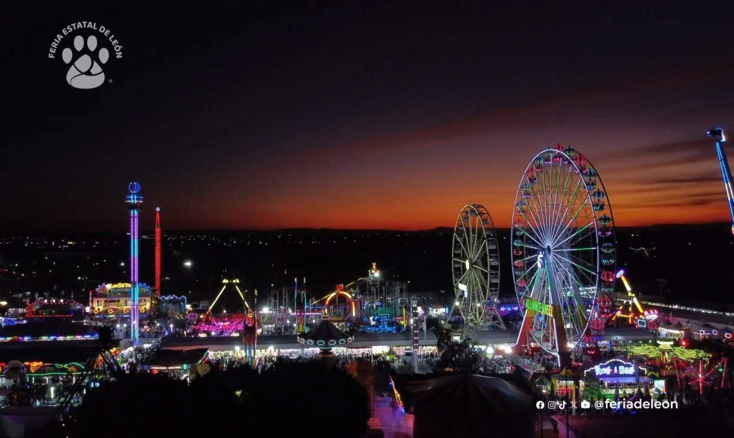Feria de León, parque de diversiones con noria gigante y juegos iluminados en la noche.