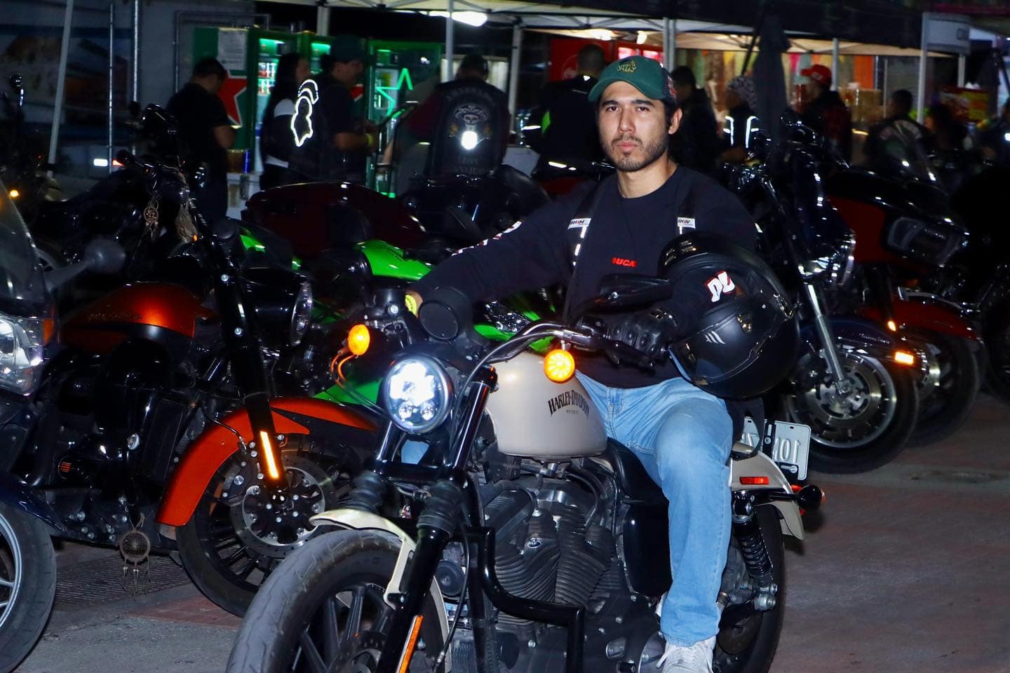 Motociclista en motocicleta en el centro de Le&oacute;n, rodeado de varias motos en un evento nocturno.