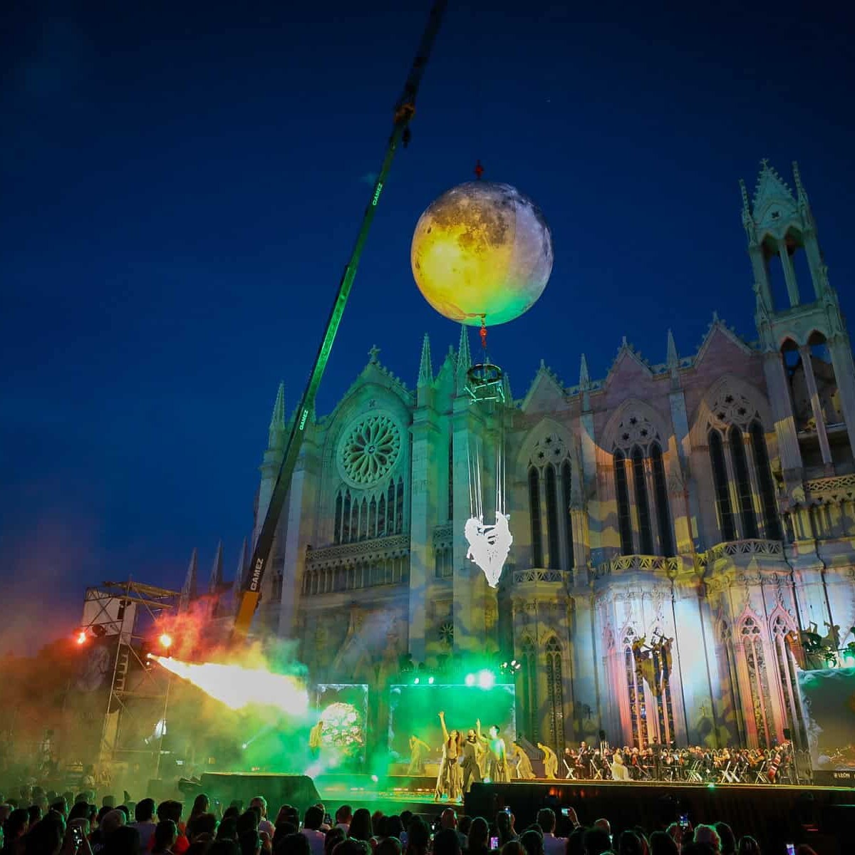 Espectáculo nocturno en la Catedral de León con luces, música y un globo gigante en el cielo, creando un ambiente mágico y fe.
