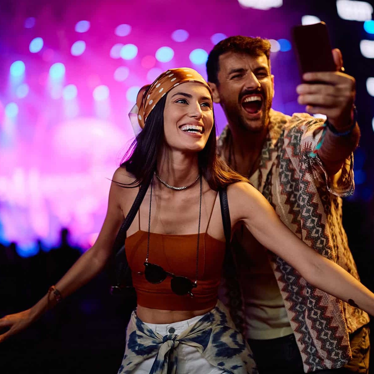 Personas disfrutando un concierto en vivo con luces de escenario vibrantes.