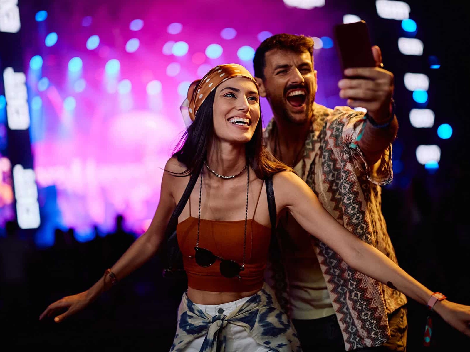 Personas disfrutando un concierto en vivo con luces de escenario vibrantes.