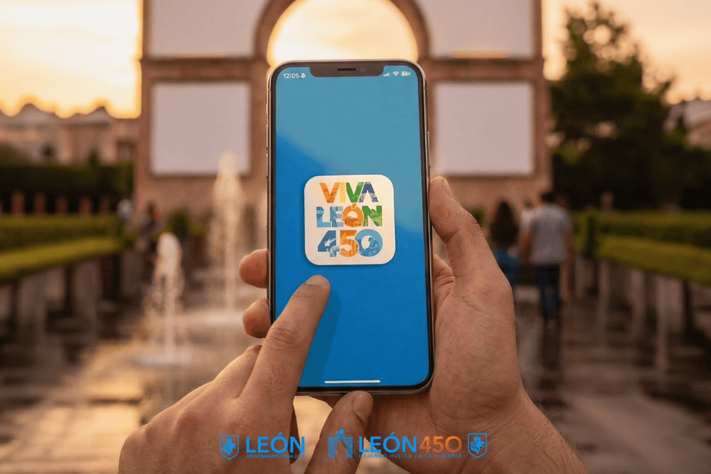 Persona sosteniendo un teléfono con el logo de Viva León 450 en un fondo de monumento y fuentes al atardecer.