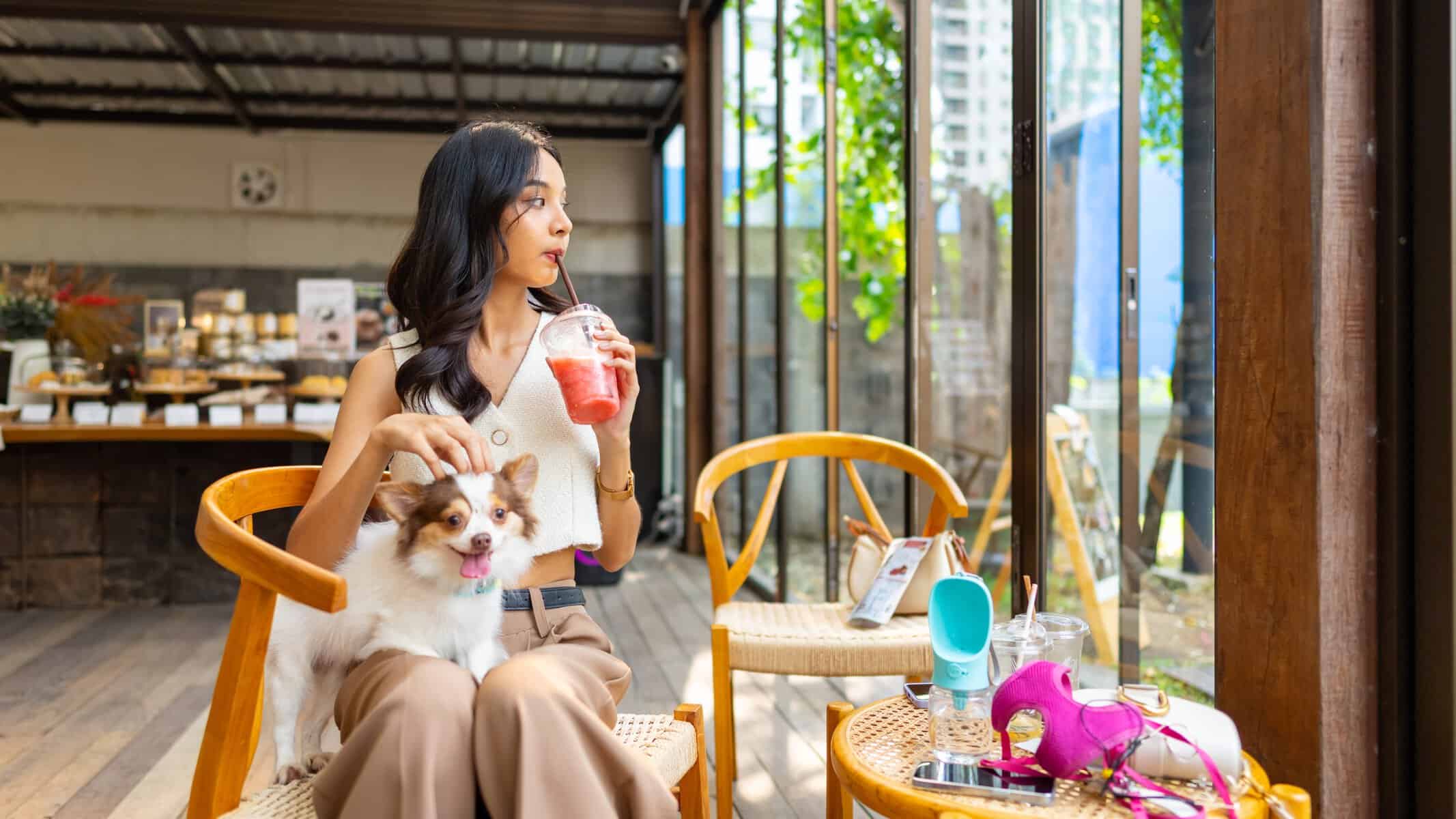 Mujer disfrutando en cafeter&iacute;a de Le&oacute;n con su perro, ambiente acogedor y moderno, ideal para turistas y locales.