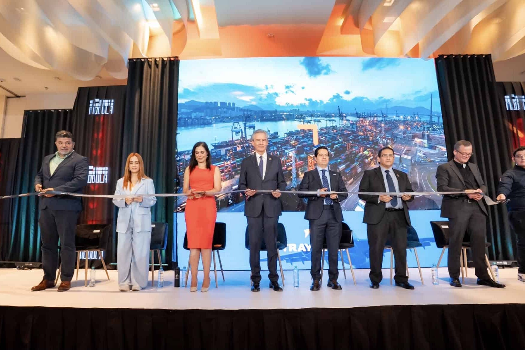 Grupo de personas en un escenario durante una inauguración con pantalla grande de fondo en León, Guanajuato, México.