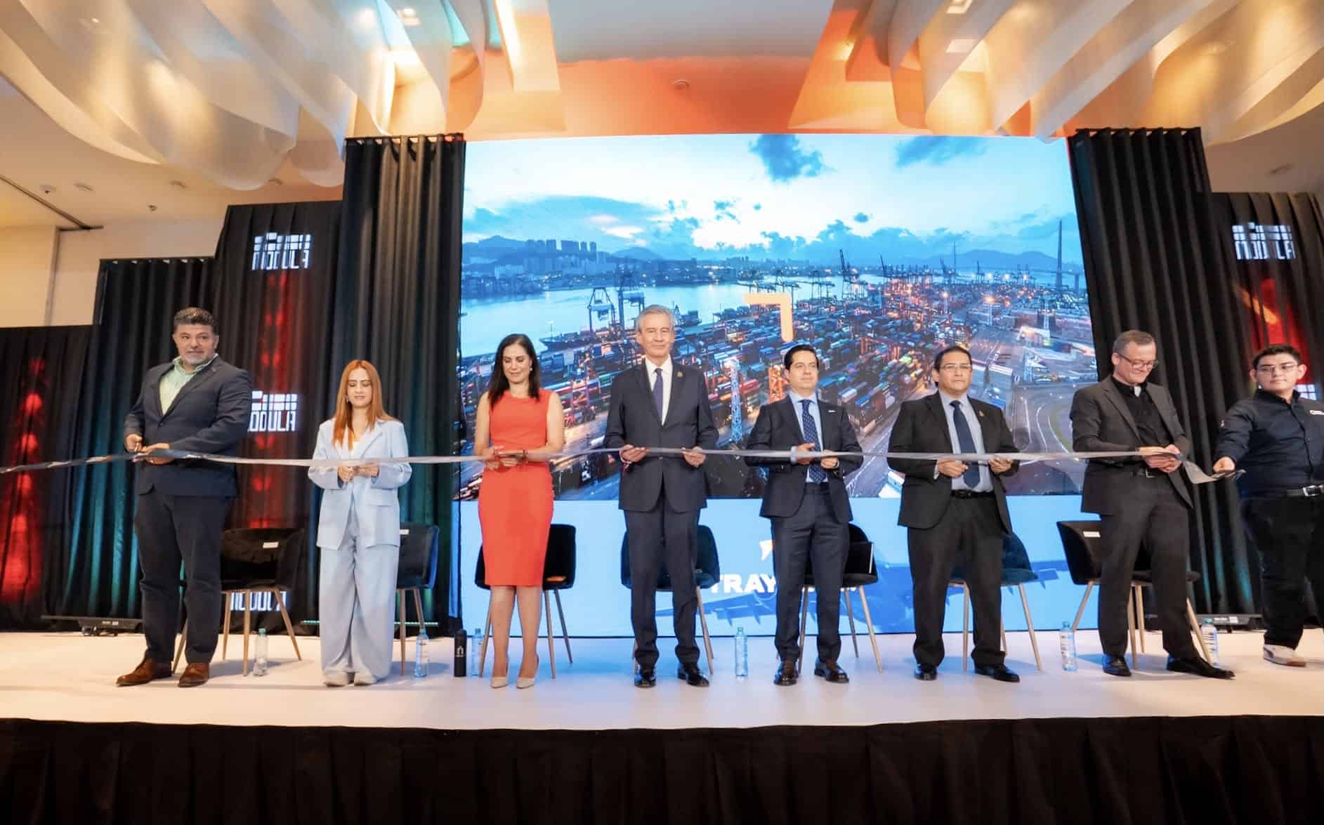 Grupo de personas en un escenario durante una inauguración con pantalla grande de fondo en León, Guanajuato, México.