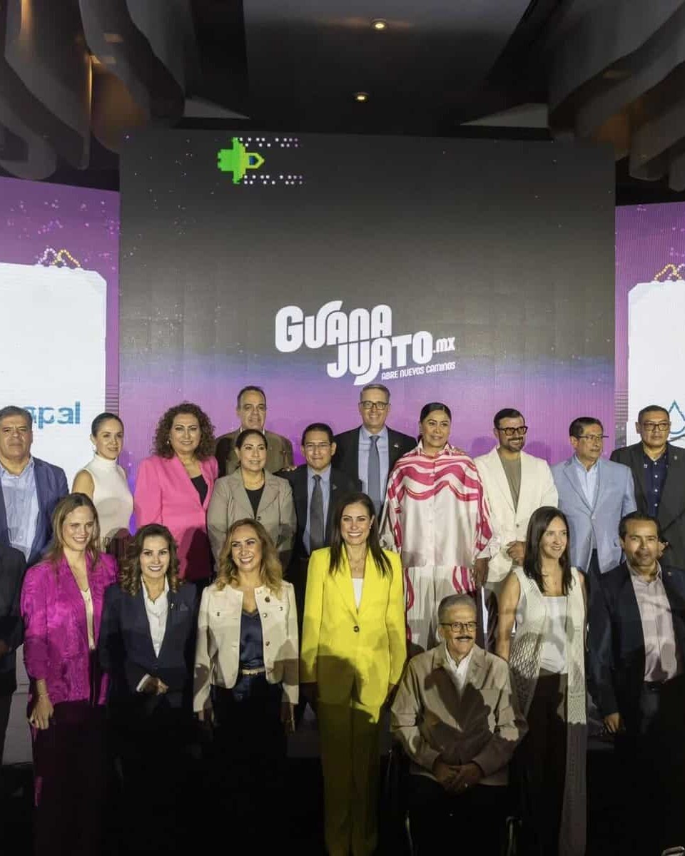 Grupo de personas en un evento cultural en León, Guanajuato, con escenario y pantallas grandes de fondo.