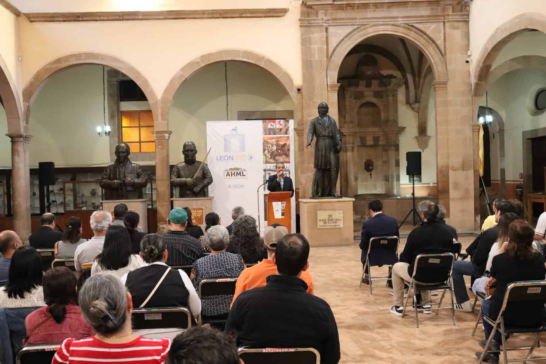 Conferencia en León Guanajuato con público y orador en escenario histórico.