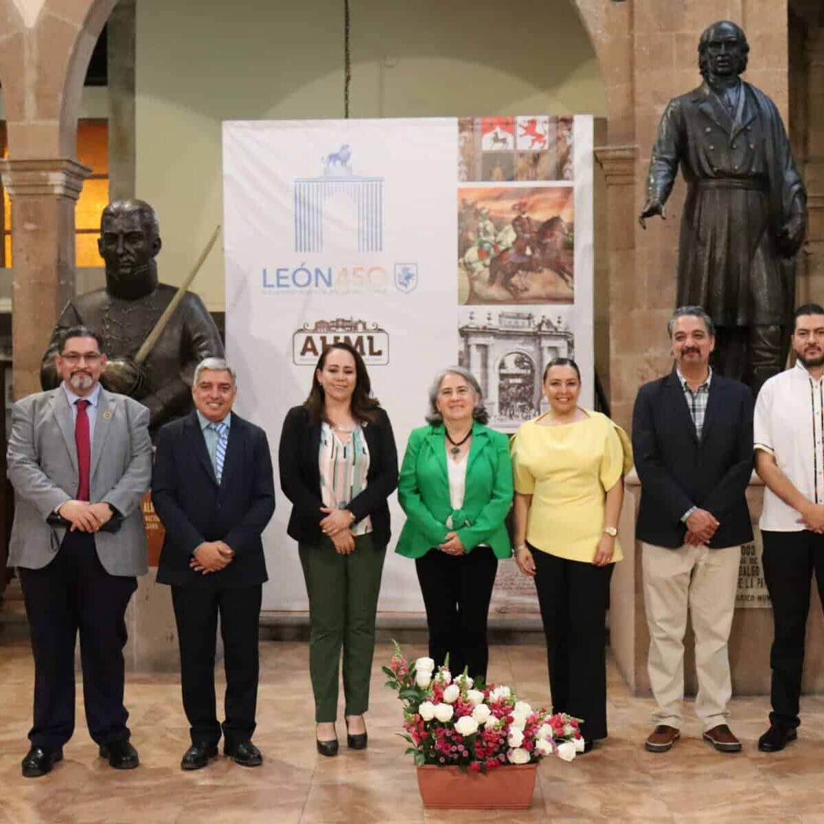 Grupo de personas en evento cultural en León, Guanajuato, con estatuas y exhibiciones históricas.