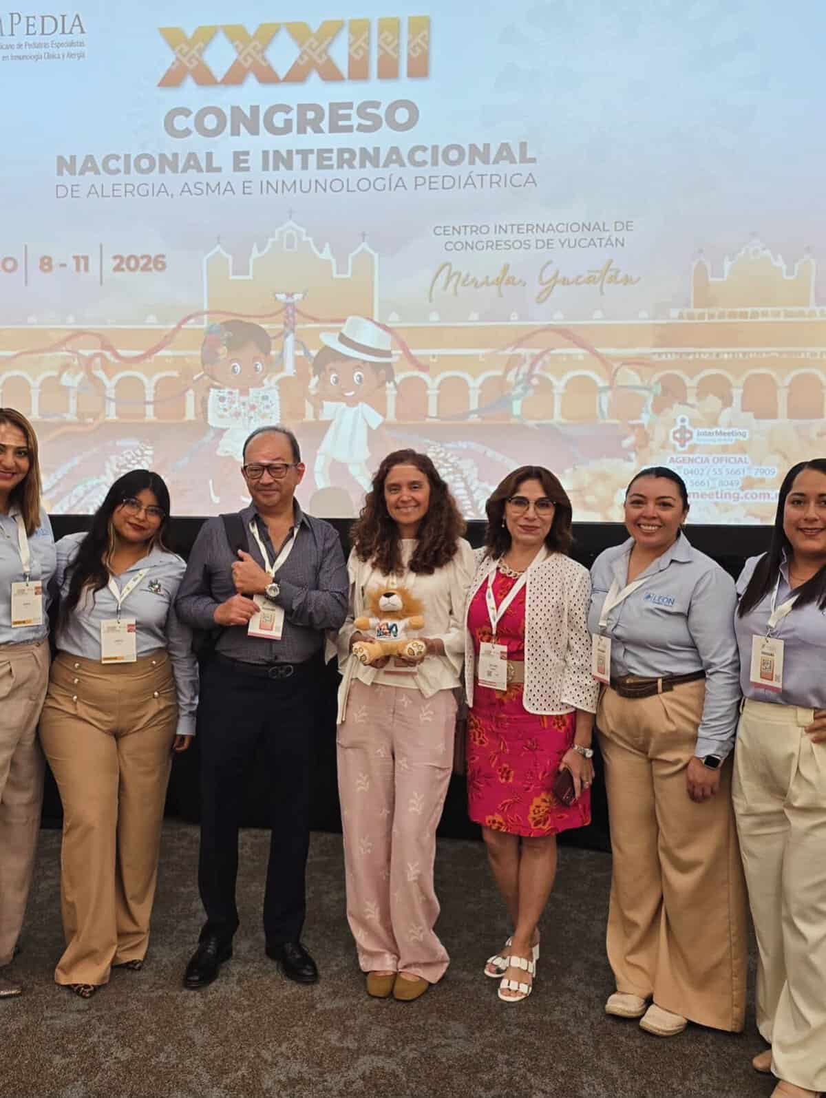 Grupo de profesionales en salud en Congreso de Alergia en León, Guanajuato, México, con cartel del evento en fondo.