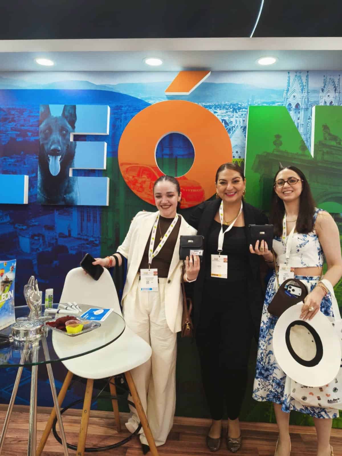 Tres mujeres en evento de salud en León, Guanajuato, mostrando productos médicos y sonriendo.
