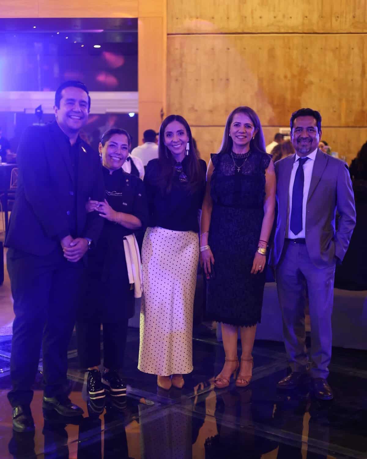 Grupo de cinco personas en evento en León, Guanajuato, México, sonriendo y vestidas formalmente en un ambiente elegante.