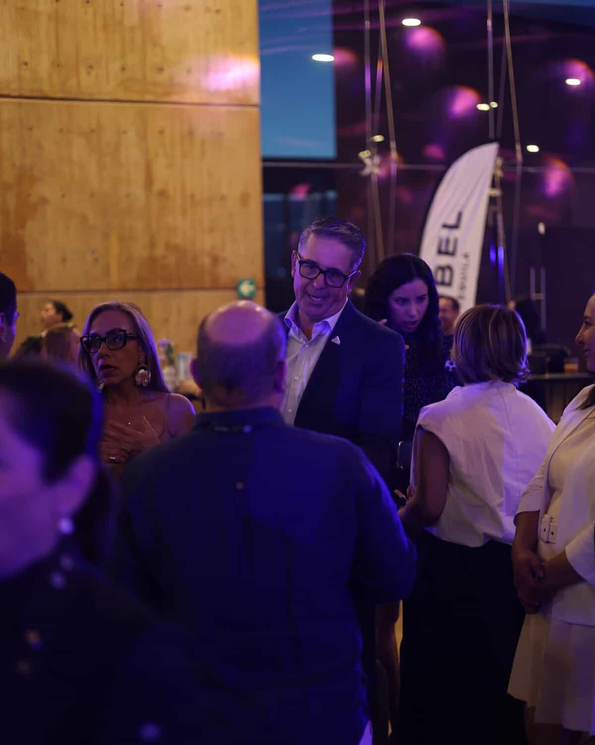 Grupo de personas en evento social en León, Guanajuato, con ambiente moderno y elegante, en un espacio con iluminación vibran.