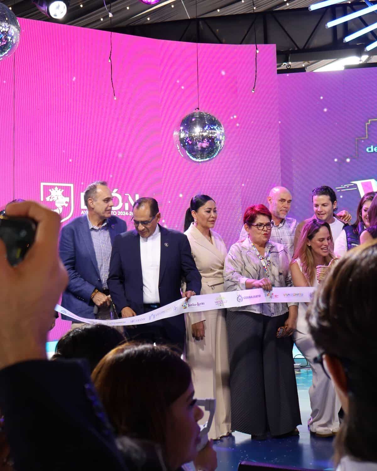 Grupo de personas en ceremonia de inauguración con fondo rosa y decoraciones festivas en León, Guanajuato.