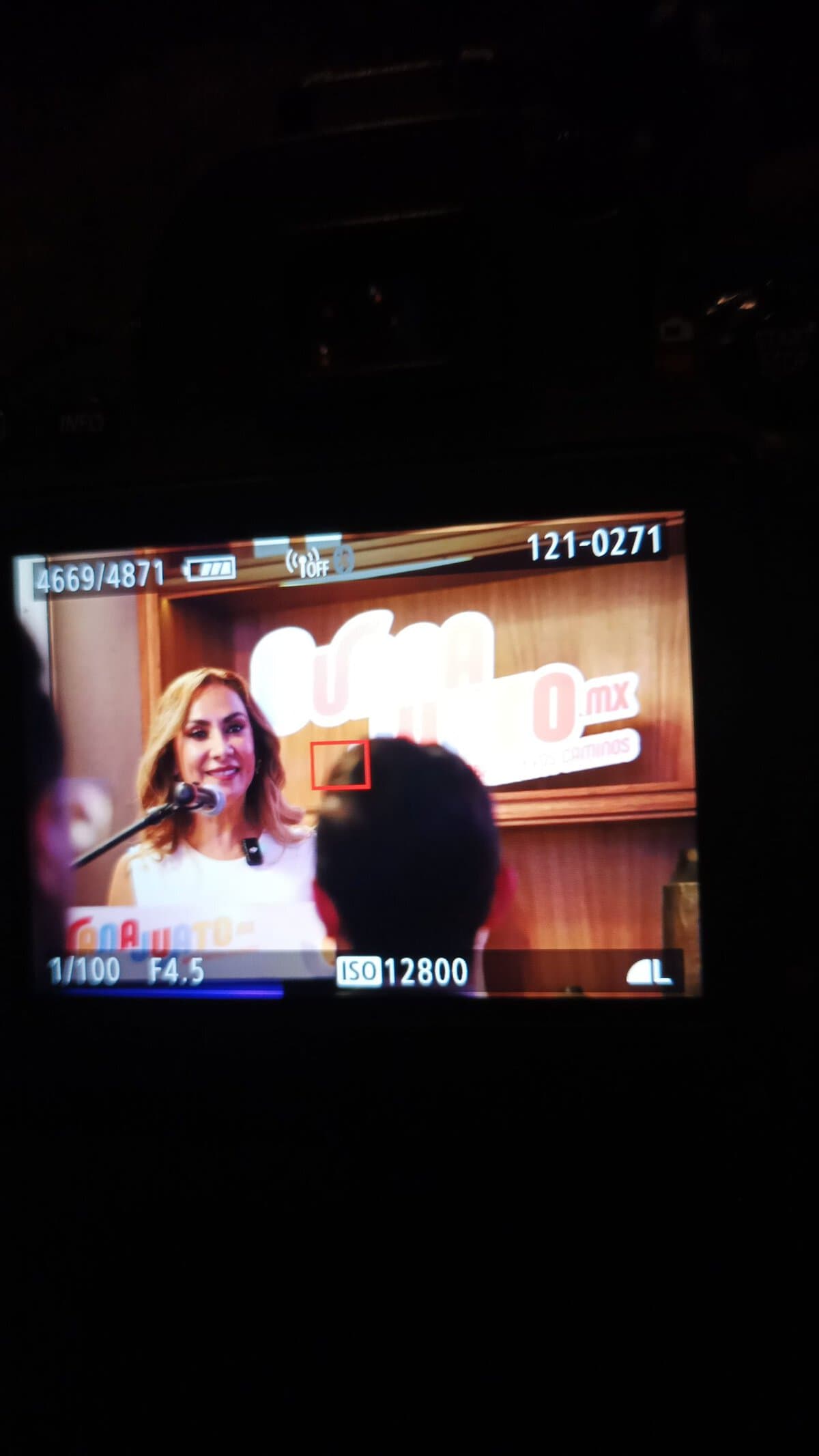 Presentadora en evento en León, Guanajuato, México, hablando frente a audiencia en un escenario.