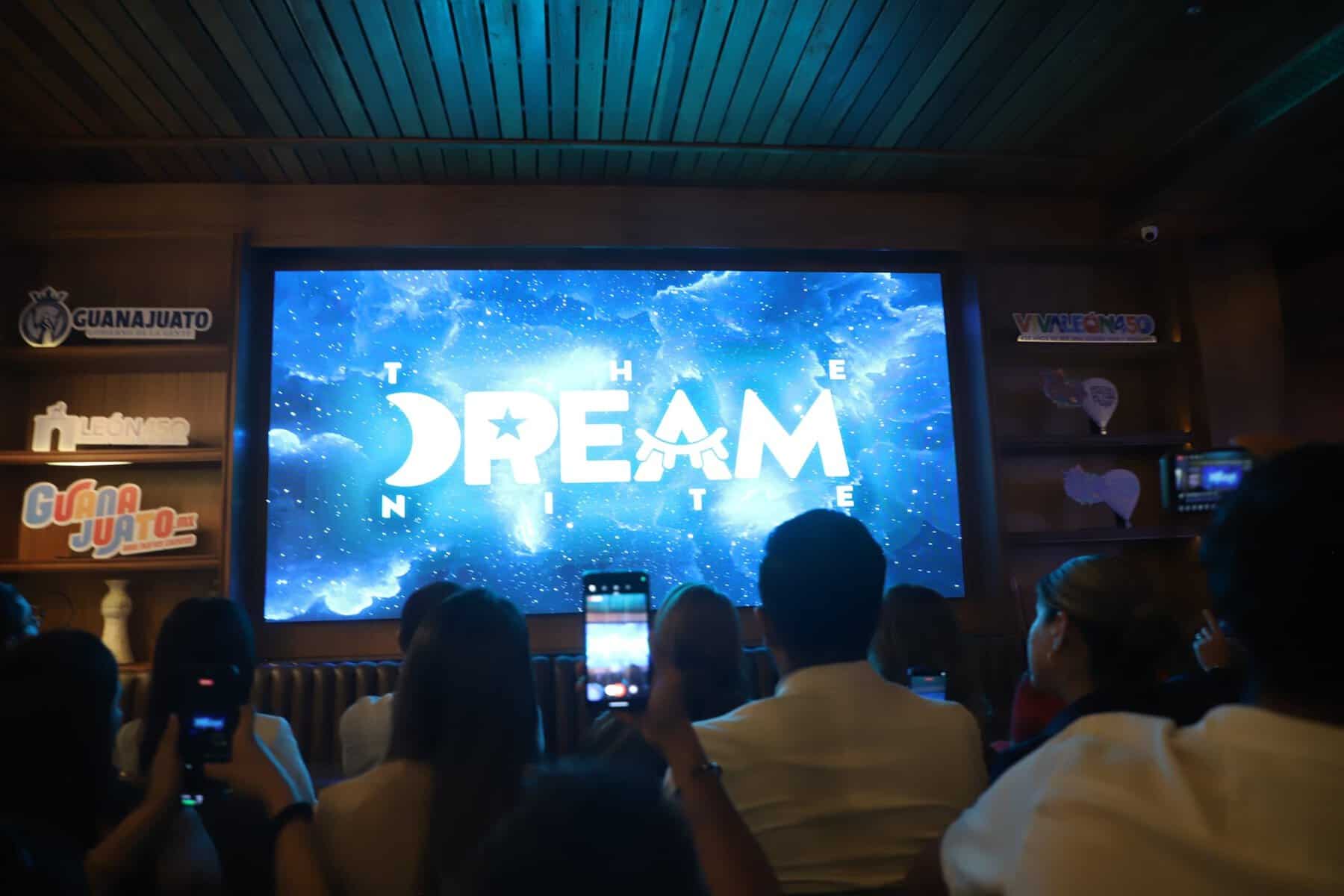 Personas viendo una presentación en una sala con pantalla grande que dice 'The Dream' en León, Guanajuato, México.