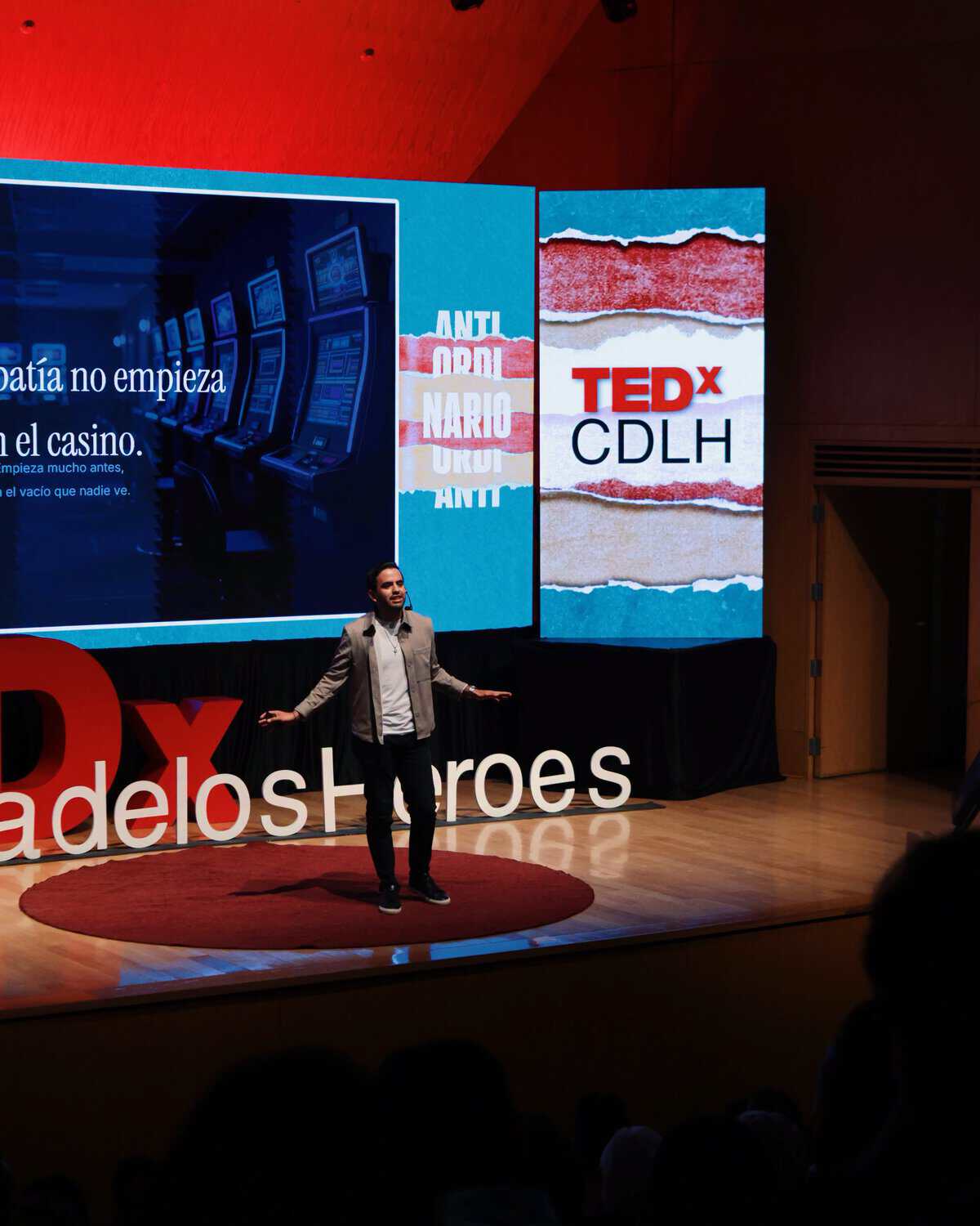 Hombre dando una charla en un escenario con pantallas grandes en TEDx León, evento de ideas y liderazgo en Guanajuato.