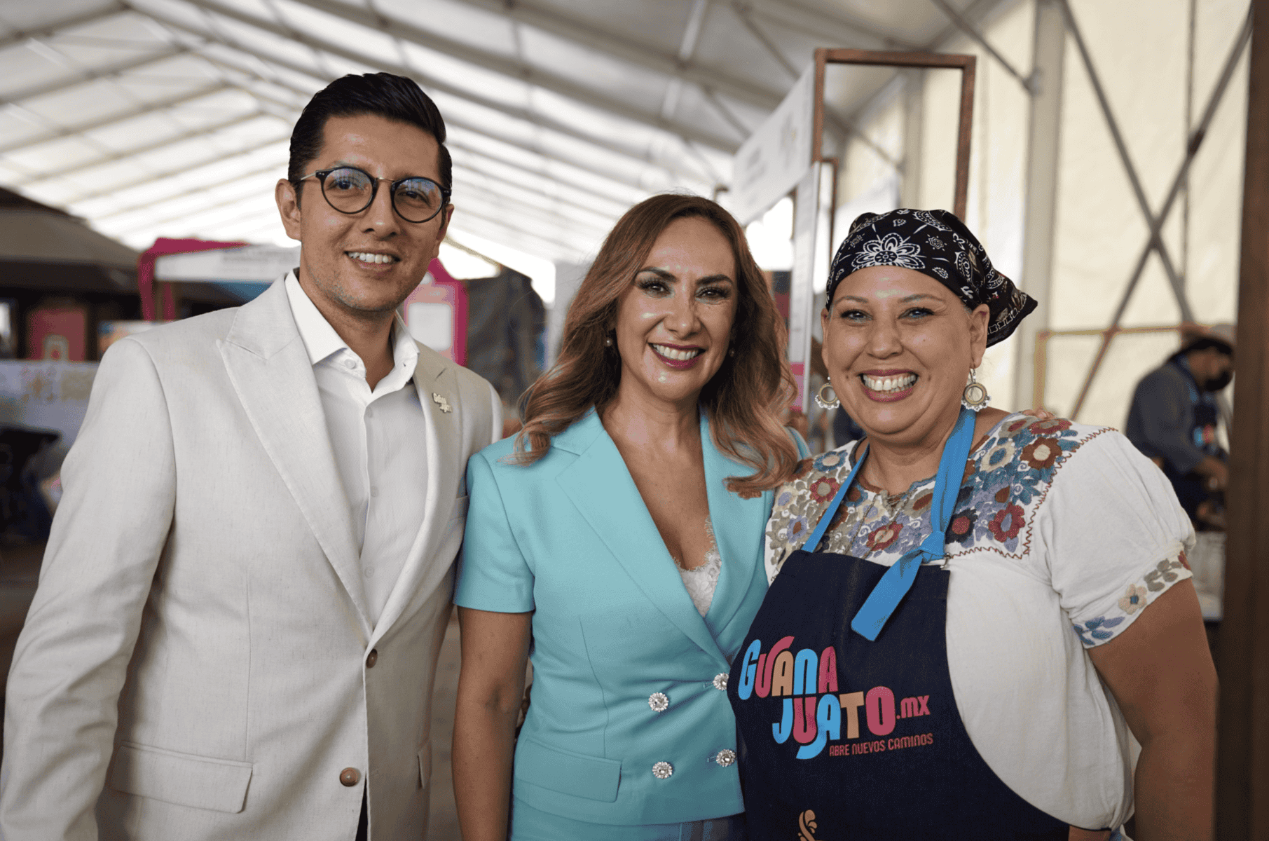 Tres mujeres y un hombre en evento, sonriendo, en un ambiente de feria, con vestimenta formal y casual, en León, Guanajuato.
