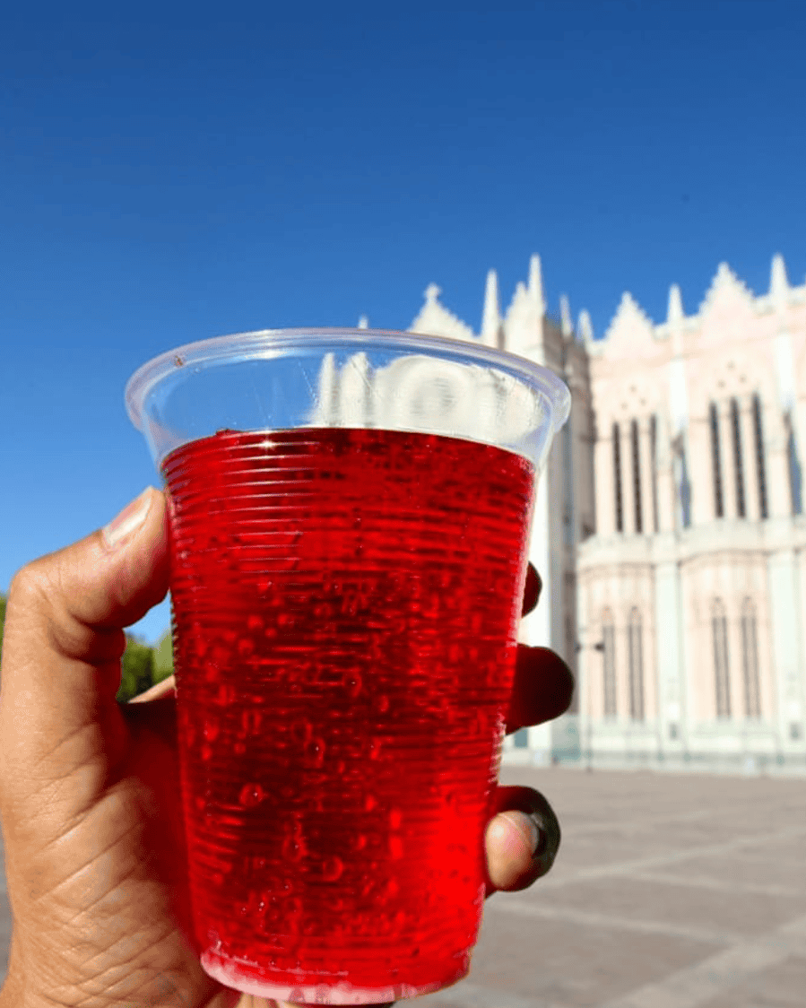 Vaso con bebida roja en Plaza Principal de León, Guanajuato, con catedral en el fondo, turismo en México.