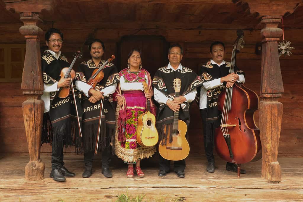Grupo de m&uacute;sicos tradicionales de Le&oacute;n Guanajuato con instrumentos t&iacute;picos en escenario de madera.