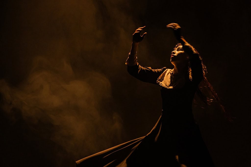 Bailarina en escena durante una presentaci&oacute;n art&iacute;stica en Le&oacute;n, Guanajuato, con iluminaci&oacute;n dram&aacute;tica y ambiente cultural.