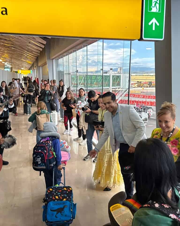 Personas en aeropuerto de León con maletas y música en vivo, esperando vuelos internacionales.