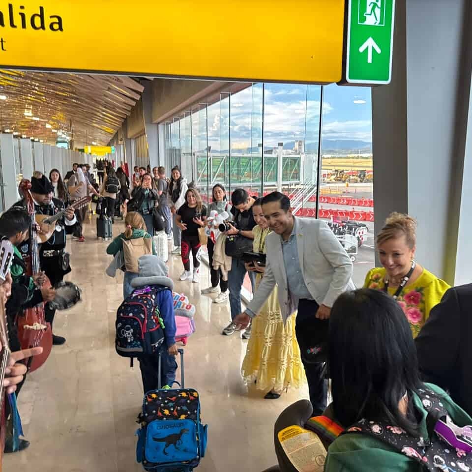 Personas en aeropuerto de León con maletas y música en vivo, esperando vuelos internacionales.