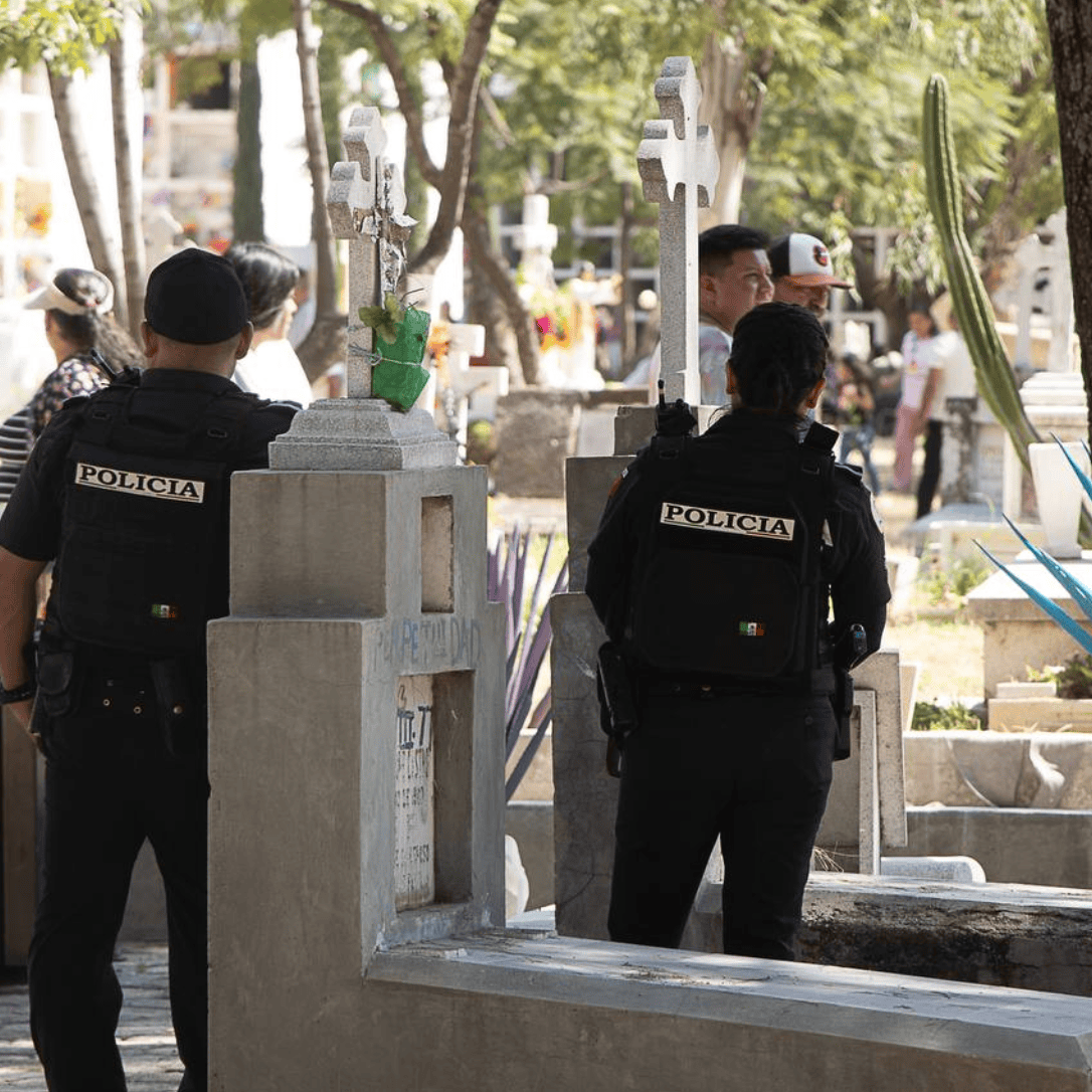 Policía vigila un cementerio de León durante Día de Muertos, escena de seguridad y tranquilidad.