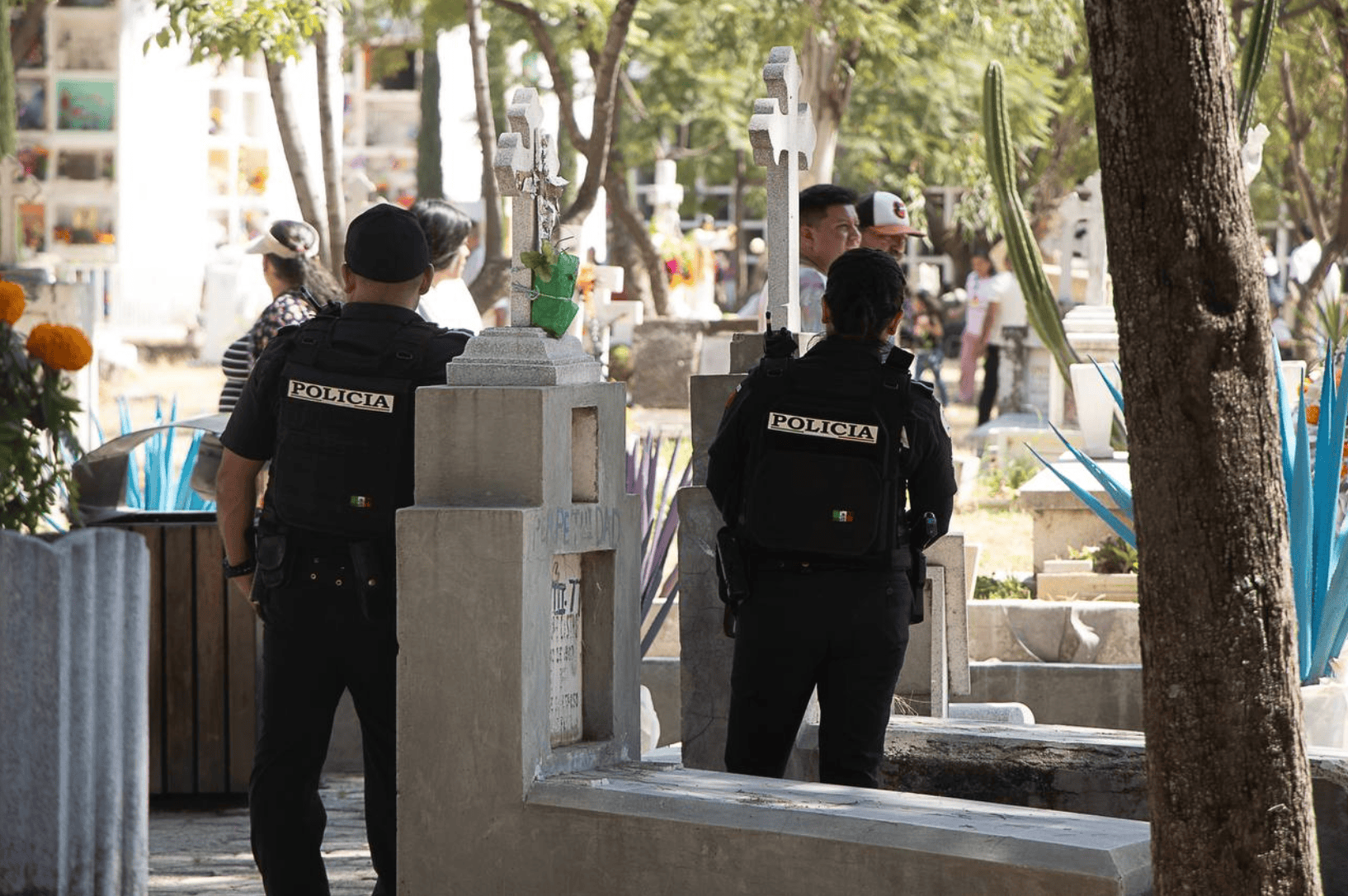 Policía vigila un cementerio de León durante Día de Muertos, escena de seguridad y tranquilidad.
