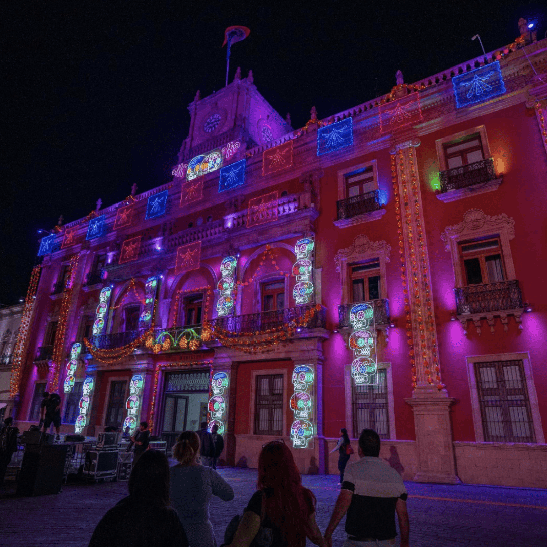 Fachada del Palacio de León iluminada con luces de colores durante el Festival de la Muerte 2026.